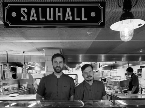 Två kockar bakom fiskdisken under skylten SALUHALL, märkta fisksorter på is